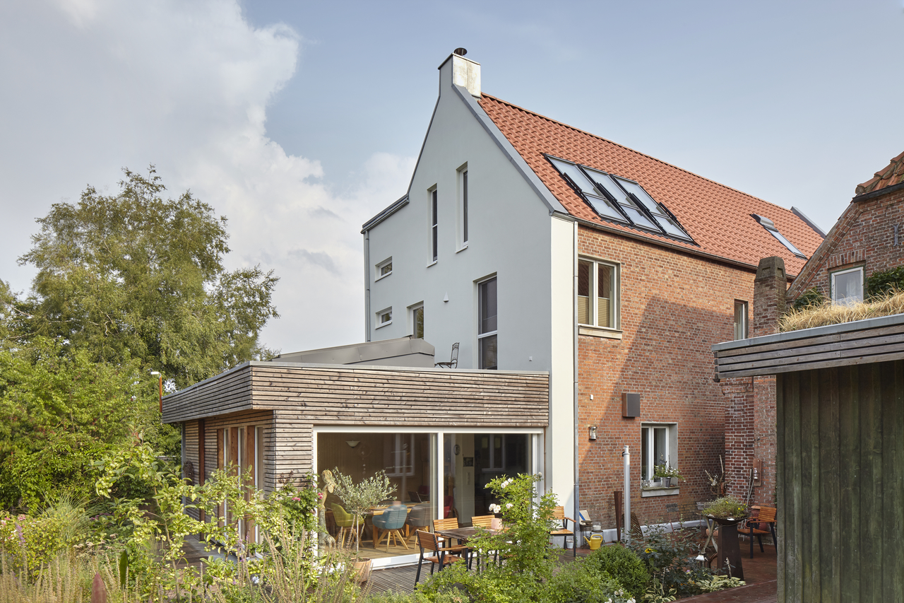 An image of roof with two open sloped roof windows and the trees in the background