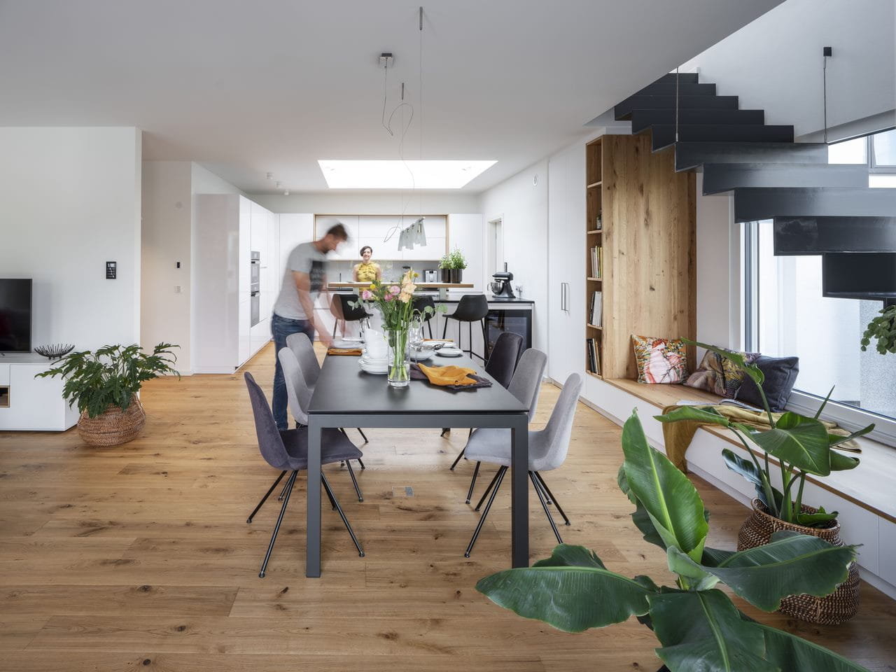 Kitchen and home office area in the house. Woman is standing by the kitchen cabinet."