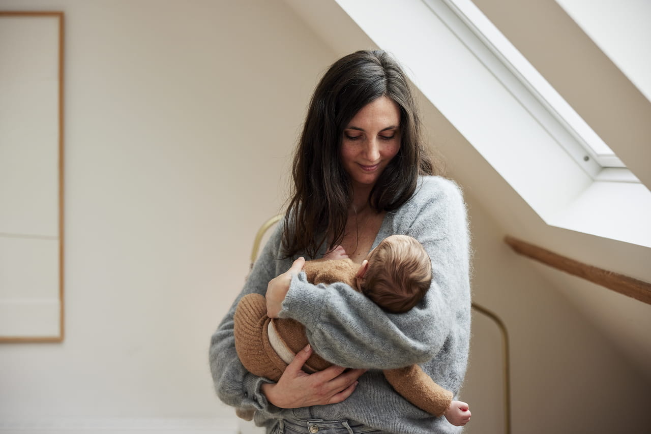 Mom holding her baby in bedroom with VELUX roof windows