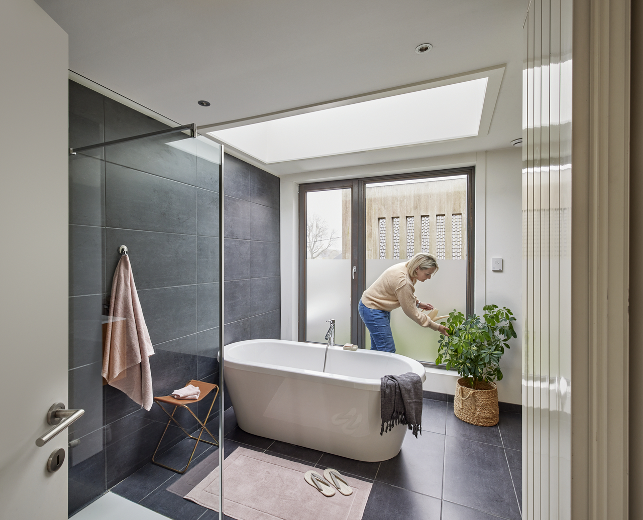 Woman standing in her bathroom with a VELUX flat roof window