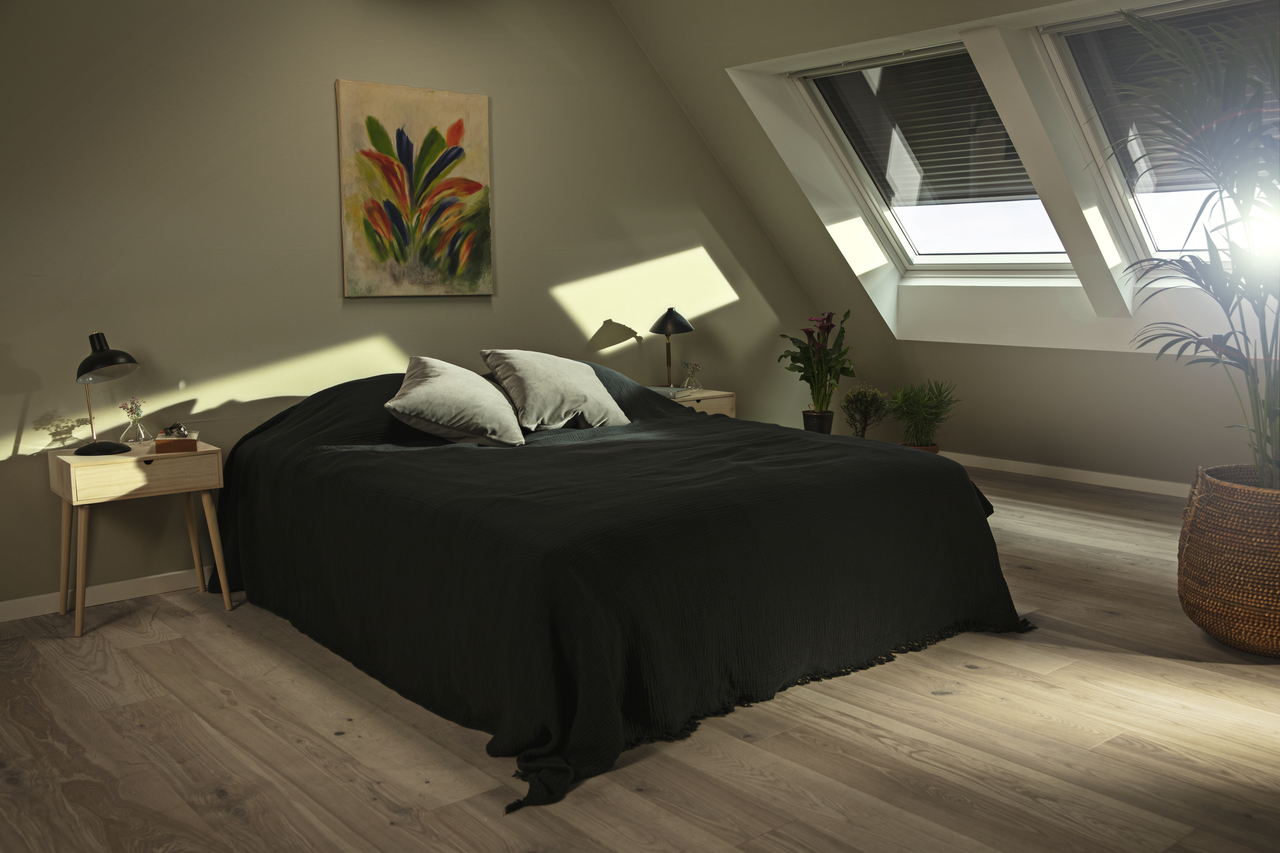 Bedroom with a double bed and roof windows covered with roller shutters