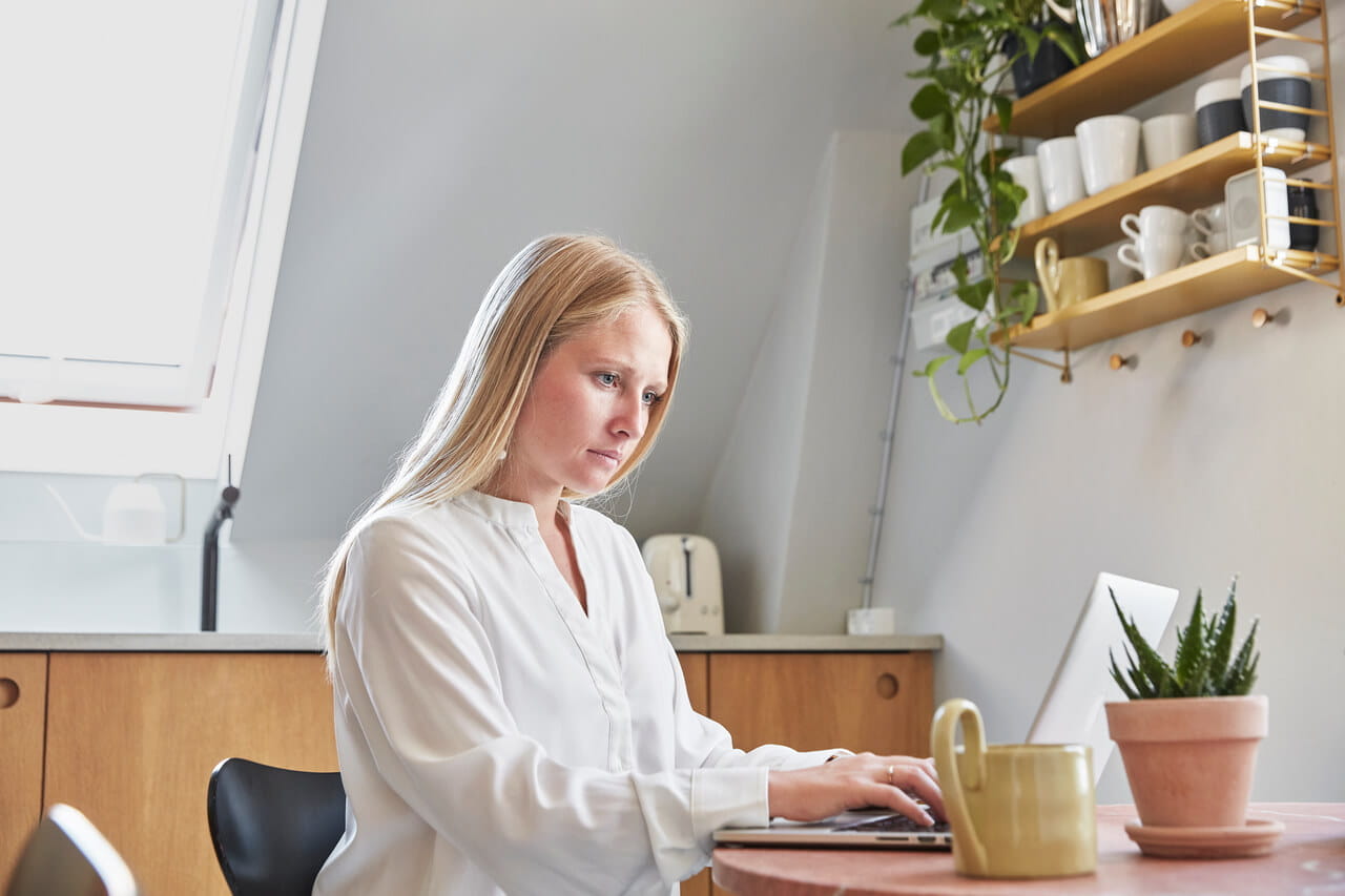 Woman sitting by the table and working on her laptop.