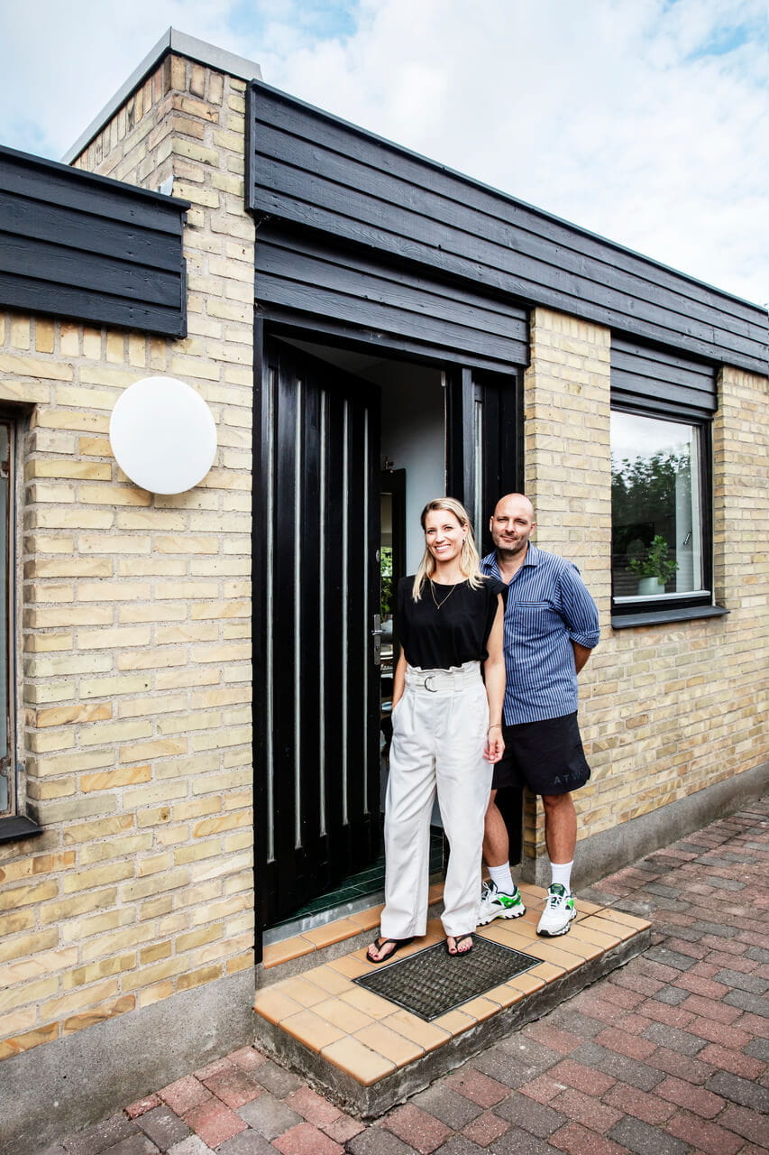 Two people posing in front of their house.