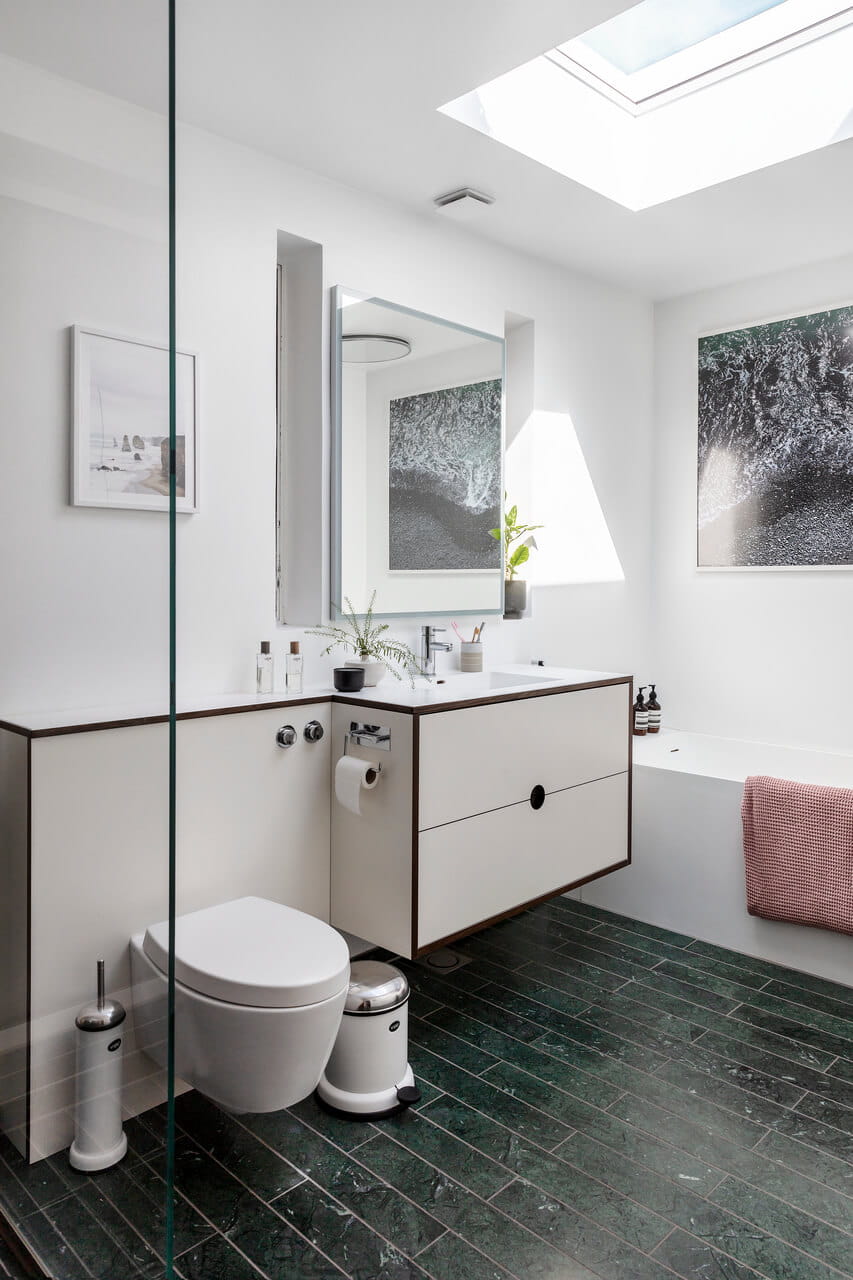 White painted bathroom with flat roof window right above the bath tub.