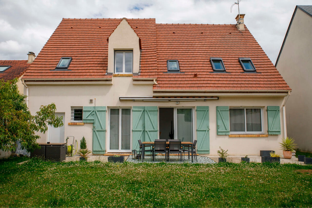 A façade of a house with red roof tile sand roof windows