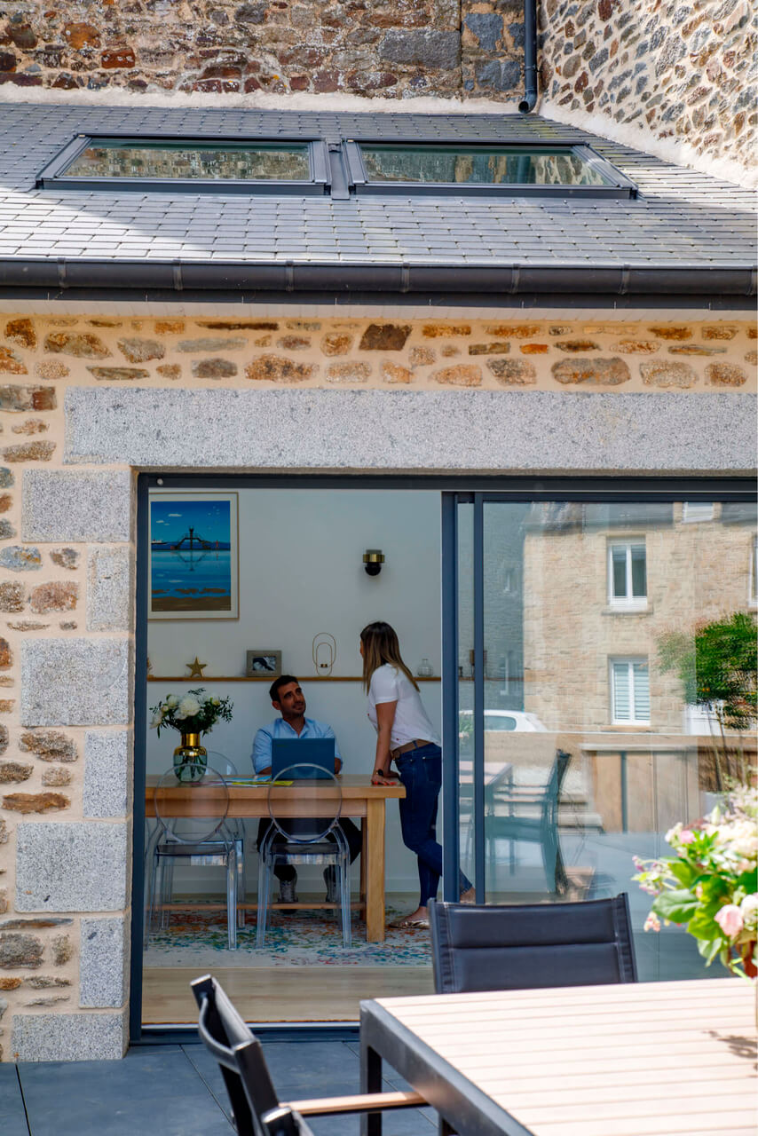 A view from the outside to a house dining area where man and woman are staying