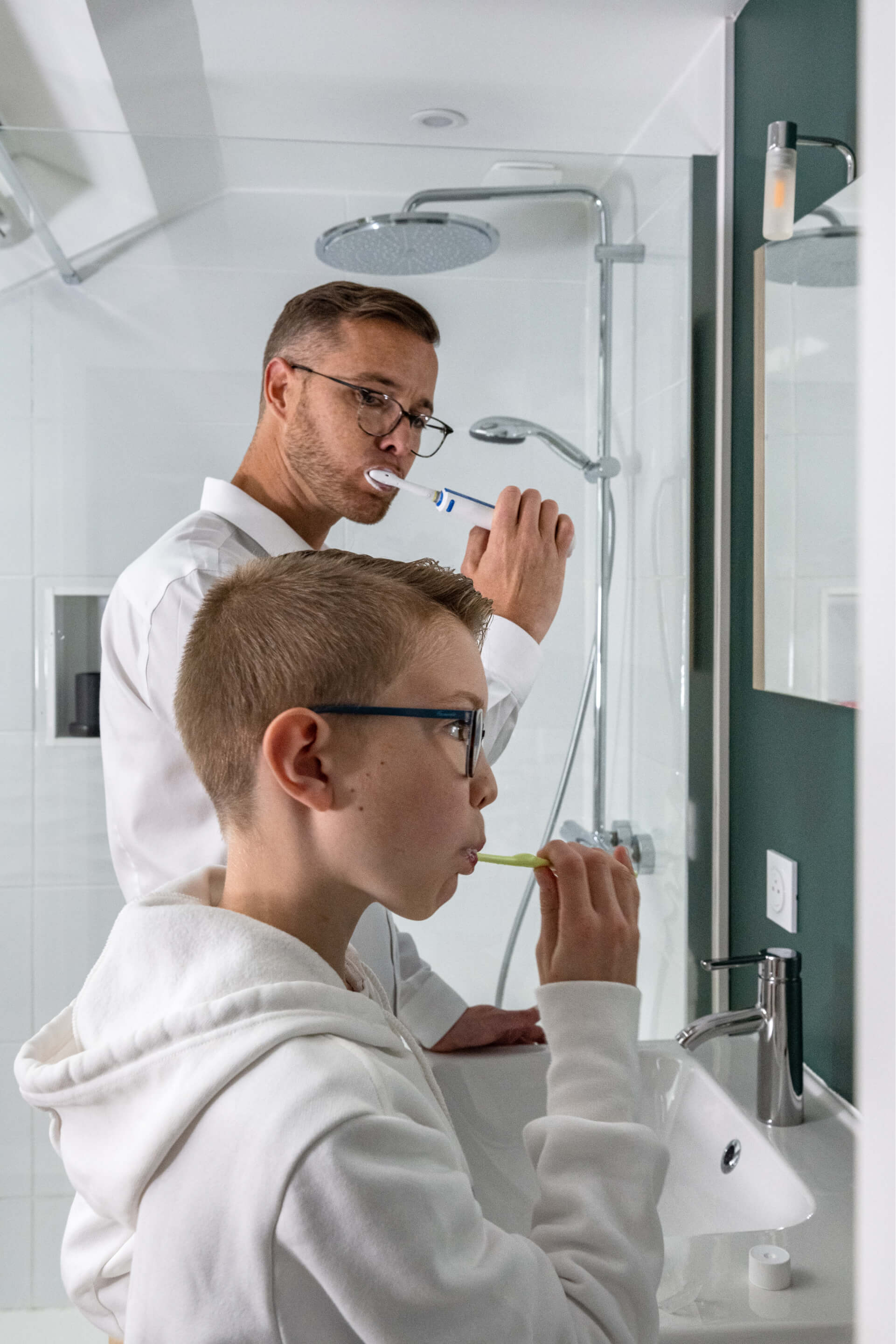 A man and a young man washing their teeth in the bathroom