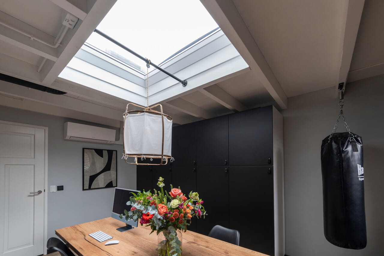 Dining room area with a big flat roof window just above the dining table.